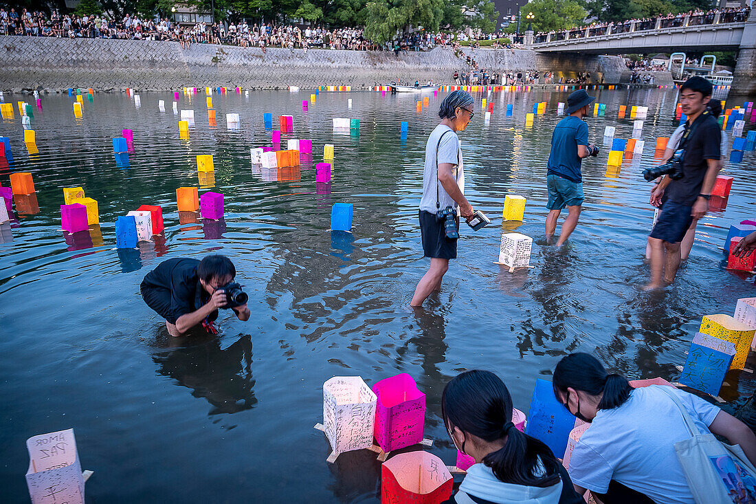 Press at work, in front of Atomic Bomb Dome with floating lamps on Motoyasu-gawa River during Peace Memorial Ceremony every August 6 in Hiroshima, Japan