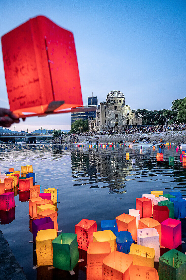 Menschen schwimmen mit Laternen auf dem Fluss, vor der Atombombenkuppel mit schwimmenden Lampen auf dem Motoyasu-gawa-Fluss während der Friedensgedenkzeremonie am 6. August in Hiroshima, Japan