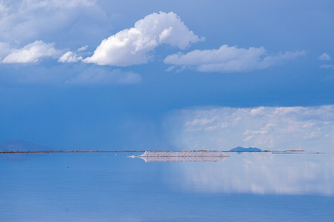 Clouds refected on a shallow sheet of water on the salt flats of Salinas Grandes in northwest Argentina with a storm over the Andes behind.