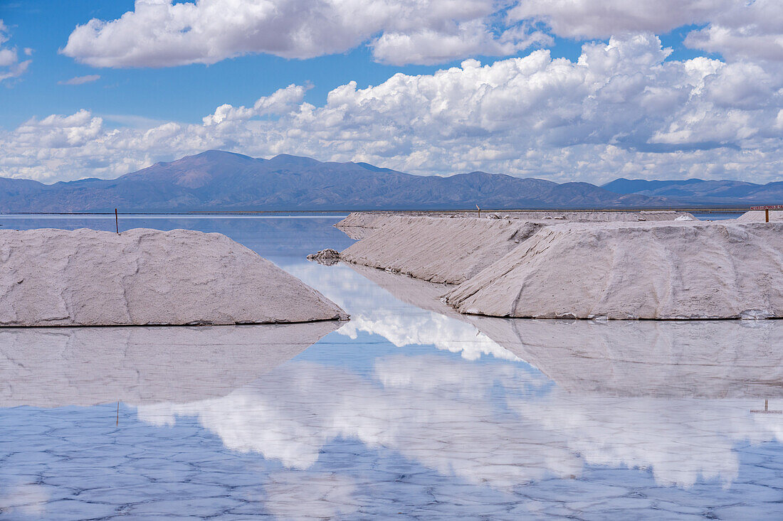 Salt mining operations on the salt flats of Salinas Grandes in northwest Argentina. Clouds are reflected on a shallow sheet of water.