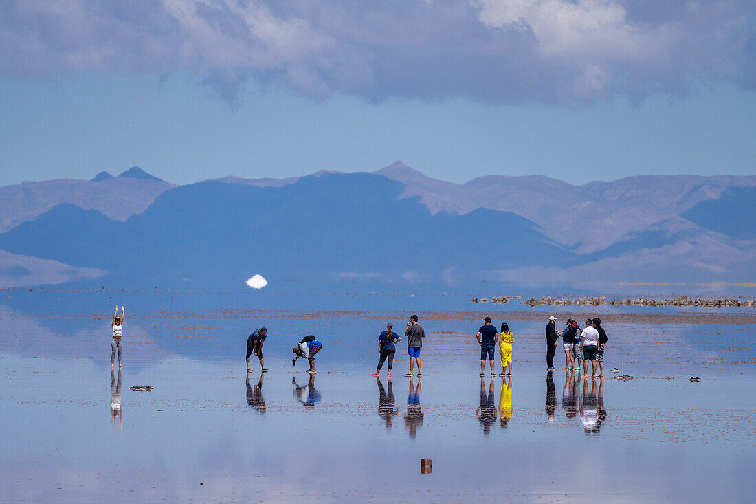 Tourists walking on the Salinas Grandes salt flats on the altiplano in Argentina. Recent rains left a shallow sheet of water on the flats.