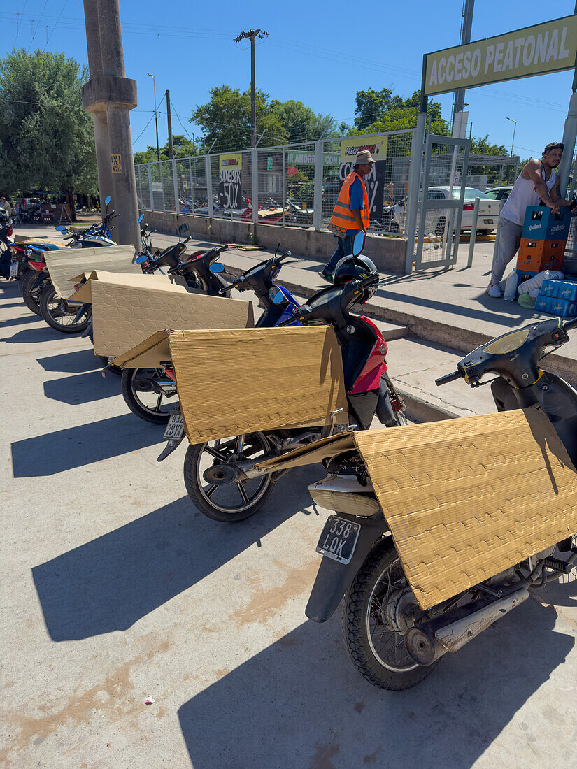 Gefaltete Pappe schützt die Sitze von geparkten Motorrädern vor einem Einkaufszentrum in Tartagal, Argentinien