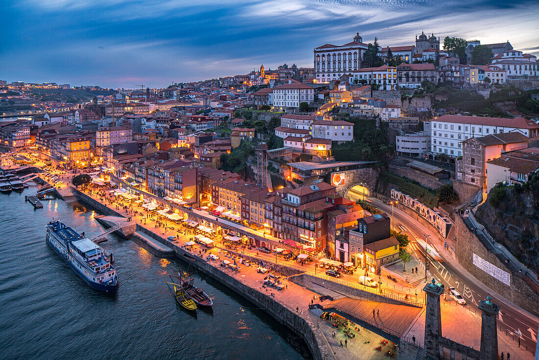 Twilight panorama of Porto, Portugal, showcasing the vibrant Cais da Ribeira and city center. Captivating city lights reflect on the Douro River, creating a picturesque evening scene.