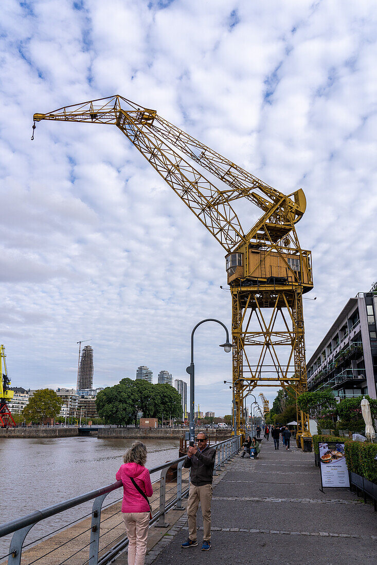 Tourists take a photo in front of a retired gantry crane in the former docks of Puerto Madero, Buenos Aires, Argentina.