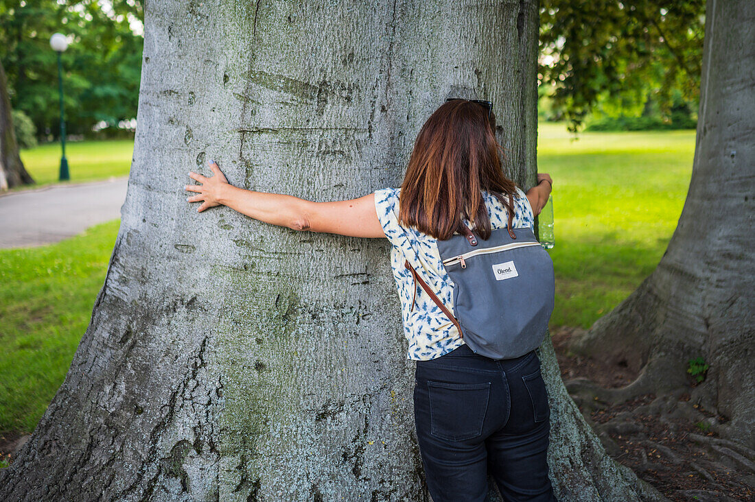 Eine Frau umarmt einen Baum in einem Park in Prag