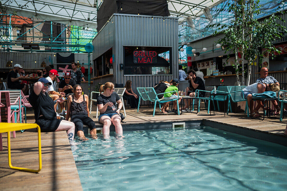 Clients refresh by the pool at Manifesto Market, a must-visit cultural experience in the heart of Prague with pop-up design retail experience bars and high-quality street food.