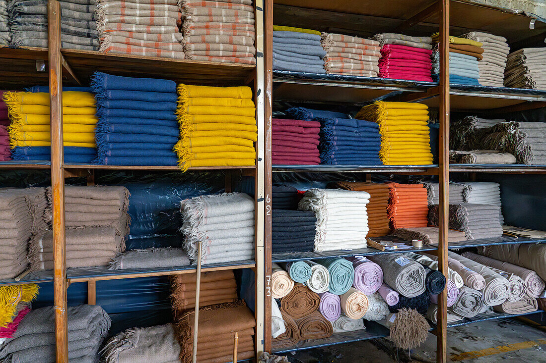 Shelves of finished woven llama-wool products at Hilandería Warmi, a weaving mill in Palpalá, Argentina.