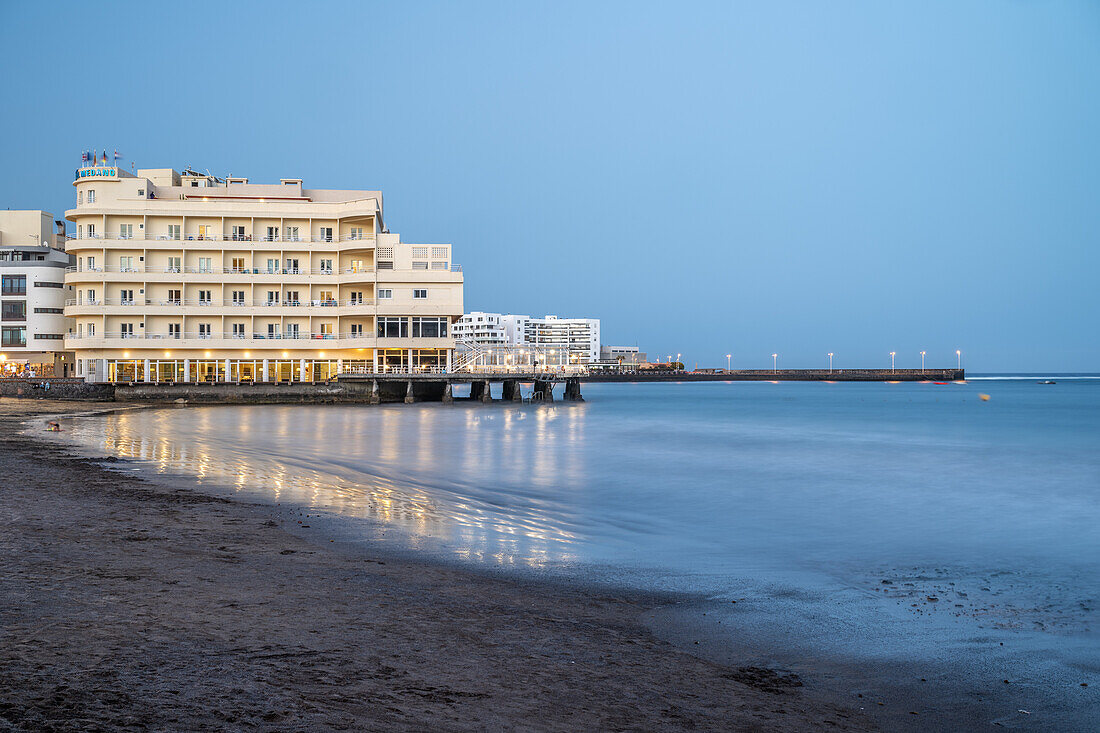 Peaceful evening beachfront view of Hotel Medano, El Medano, with reflections, in Granadilla de Abona, Tenerife, Canary Islands.