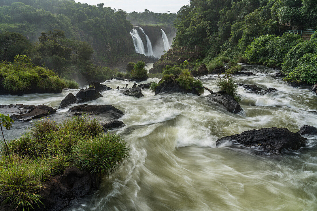 Der Nationalpark Iguazu Falls in Brasilien im Vordergrund und Argentinien im Hintergrund. Ein UNESCO-Welterbe. Im Hintergrund sind die Drei-Musterknaben-Fälle oder Salto Tres Mosqueteros zu sehen