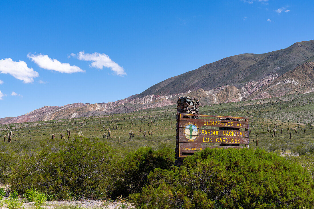 Sign at the west entrance of Los Cardones National Park with Cerro Tin Tin behind in Salta Province, Argentina.