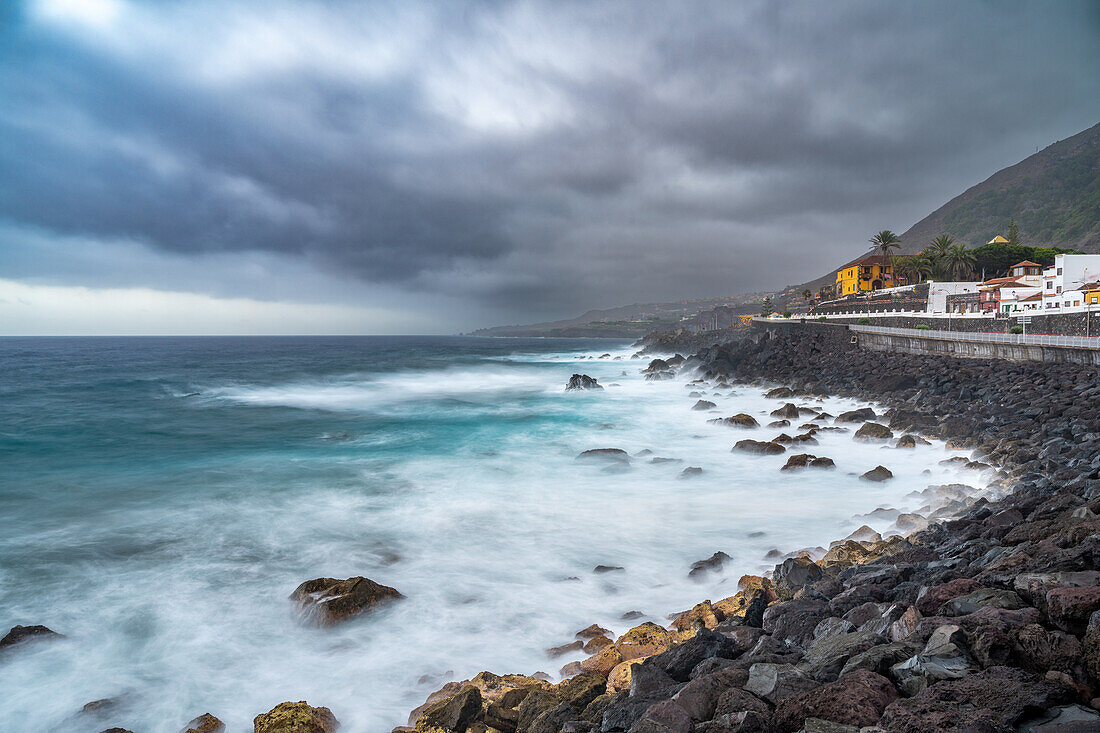 Eine atemberaubende Langzeitbelichtung der Garachico-Küste im Norden Teneriffas, Kanarische Inseln, Spanien, mit dramatischen Wolken und krachenden Wellen