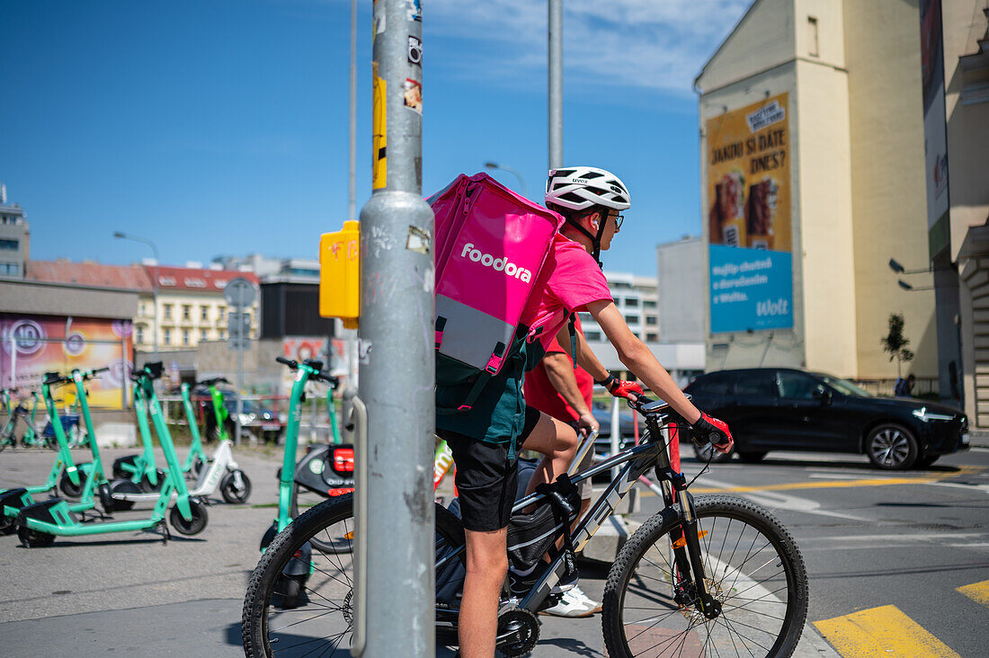 Junger Lieferjunge auf einem Fahrrad bei der Arbeit für Foodora in Prag, Tschechische Republik