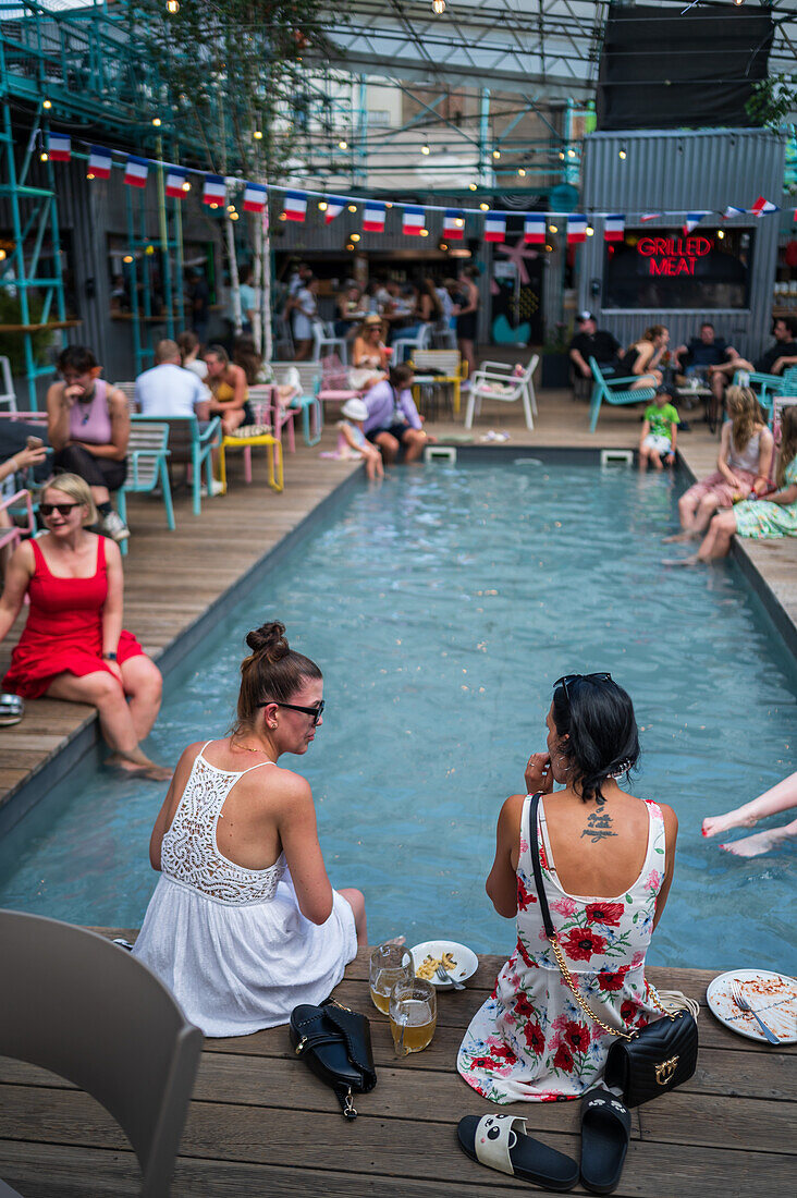 Clients refresh by the pool at Manifesto Market, a must-visit cultural experience in the heart of Prague with pop-up design retail experience bars and high-quality street food.