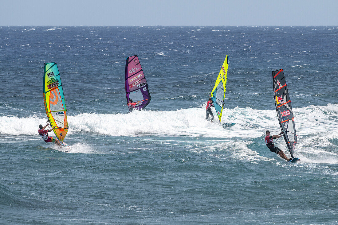 Energetic windsurfers riding the waves in El Medano, Tenerife, Spain, showcasing skill and adventure in a picturesque coastal location.