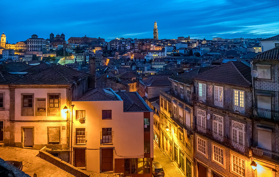 A beautiful evening cityscape of Porto, Portugal, showcasing the illuminated streets and the iconic Clerigos Tower in the background.