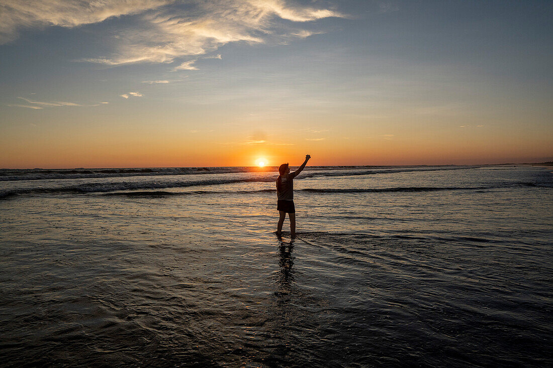 Sunset on the beach in Las Lajas, Panama. Person stands on the beach silhouetted.