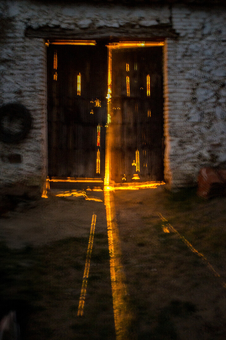 A rustic farm door beautifully illuminated by the warm glow of evening sunlight, creating a serene and mystical atmosphere.