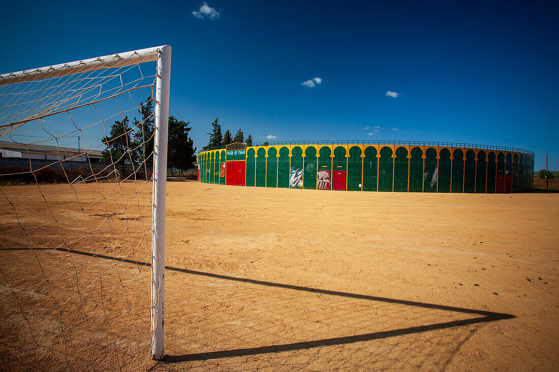 Ein einzigartiger Blick auf eine tragbare Stierkampfarena in Aznalcazar, Sevilla, Spanien, mit einem Fußballtor im Vordergrund unter einem klaren blauen Himmel