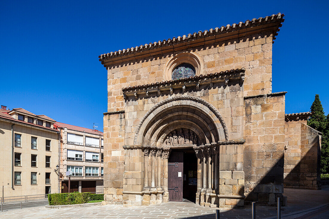 A wide shot of the San Juan de Rabanera church entrance in Soria, Spain, featuring its facade and a modern building to the left.