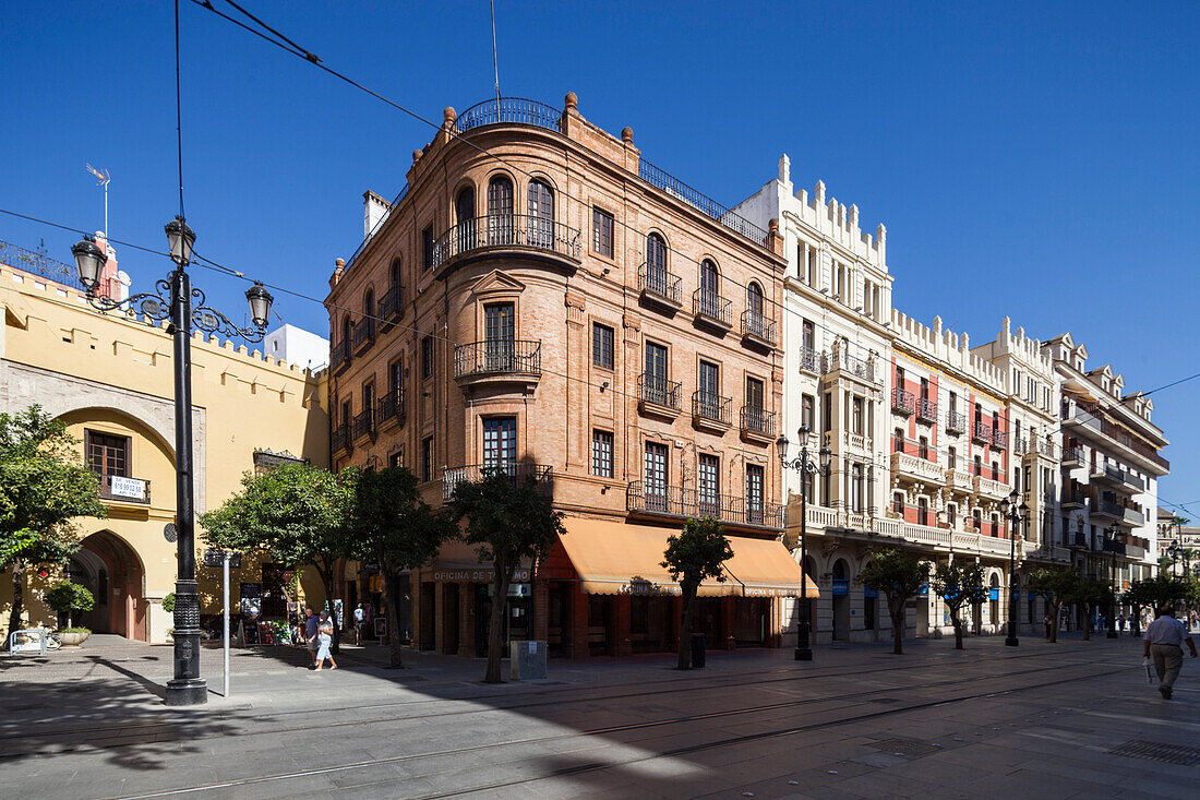 Sevilla, Spanien, 30. September 2009, In dieser belebten Straße in Sevilla befinden sich das Fremdenverkehrsamt von Sevilla aus rotem Backstein und das Gebäude der Seguros Santa Lucia inmitten des lebhaften Stadtlebens