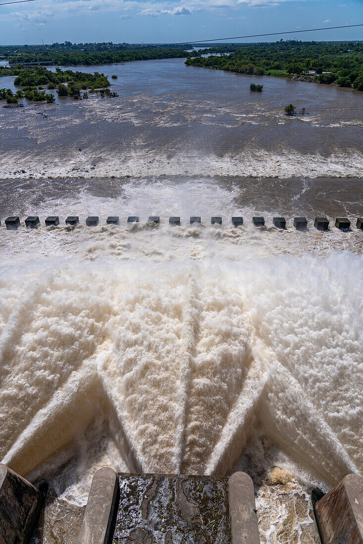 Wasserfontänen aus dem Überlauf des Rio-Hondo-Staudamms in Termas de Rio Hondo in Argentinien. Flussabwärts liegt das Naturschutzgebiet Tara Inti mit seinen kleinen Inseln