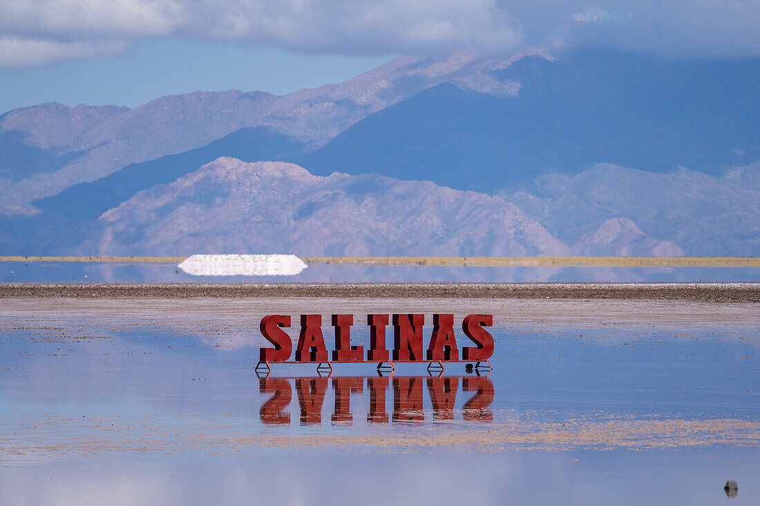 A metal sign on the Salinas Grandes salt flats on the altiplano in Argentina. Recent rains left a shallow sheet of water on the flats.