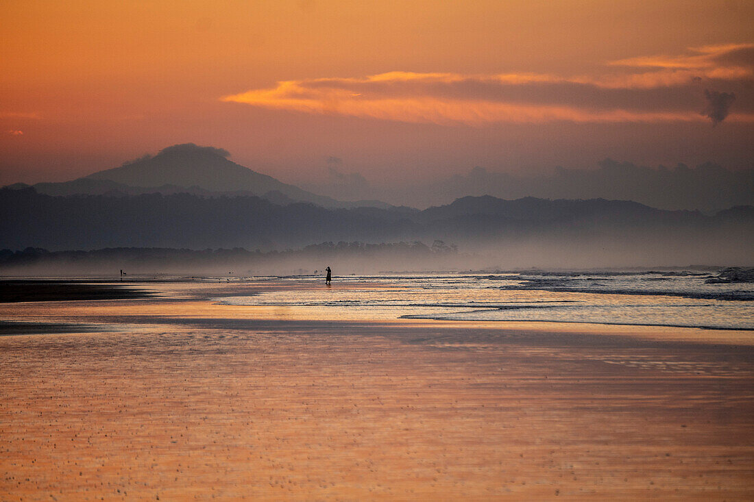 Sonnenuntergang am Strand von Las Lajas, Panama. Menschen gehen am Strand spazieren, die Silhouette ist zu sehen