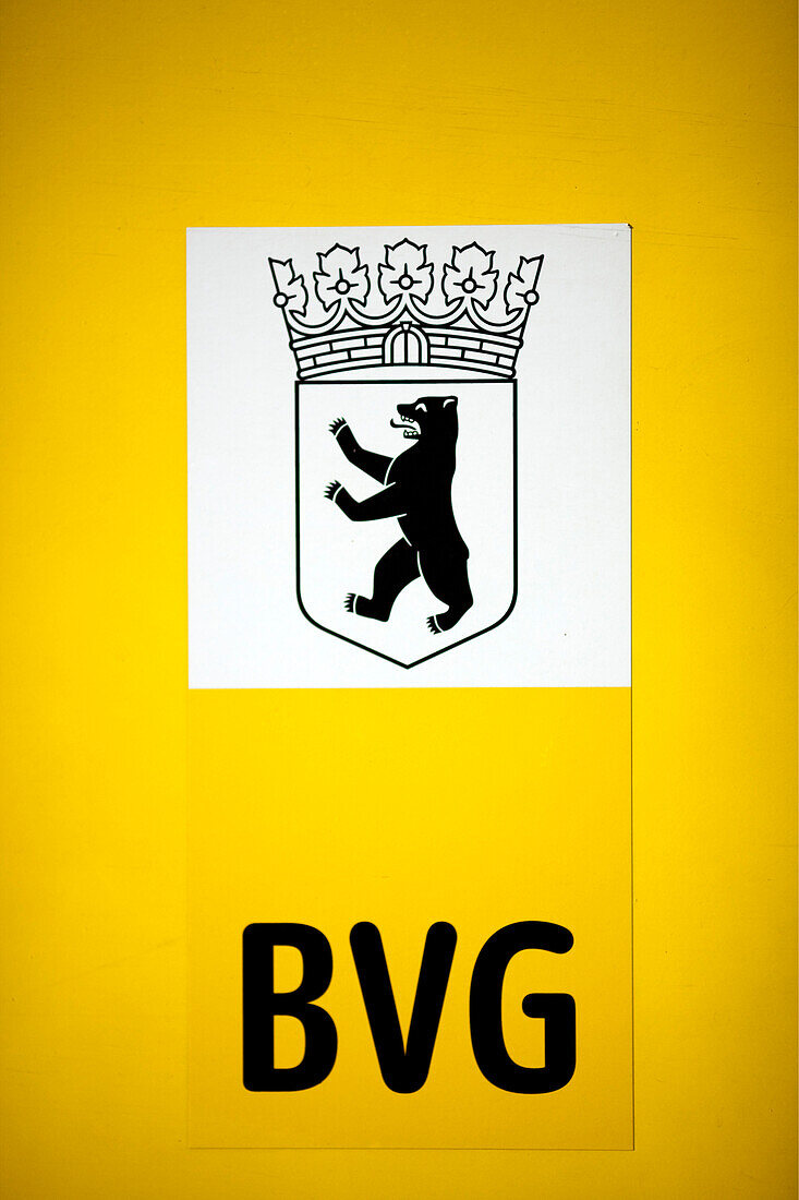 The coat of arms featuring a bear and BVG logo are displayed prominently on a yellow tram in Berlin, Germany, showcasing public transit.