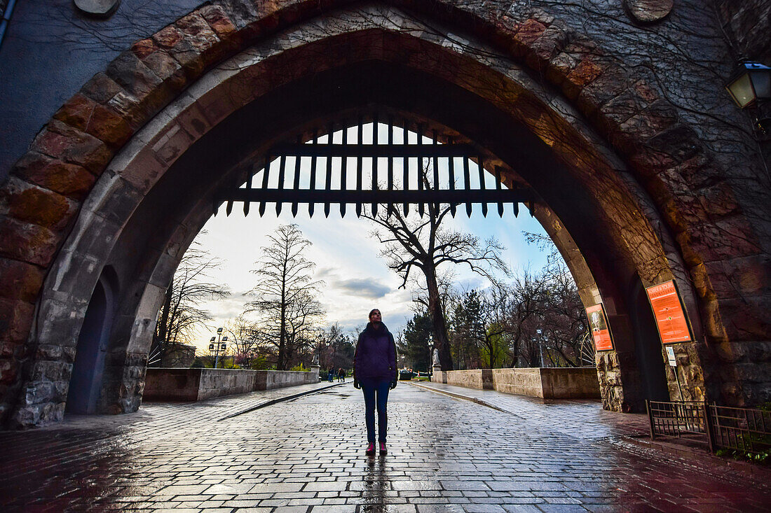 Young woman entering the gate of Vajdahunyad Castle, Budapest, Hungary