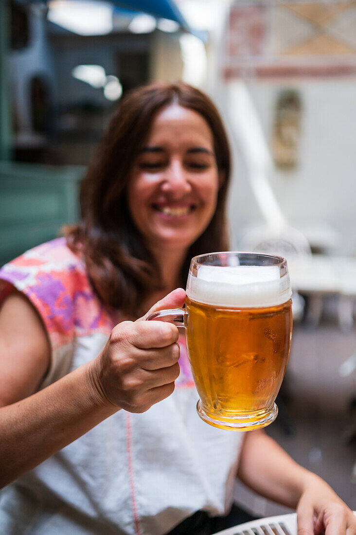 Frau hält ein Bierglas in Prag hoch