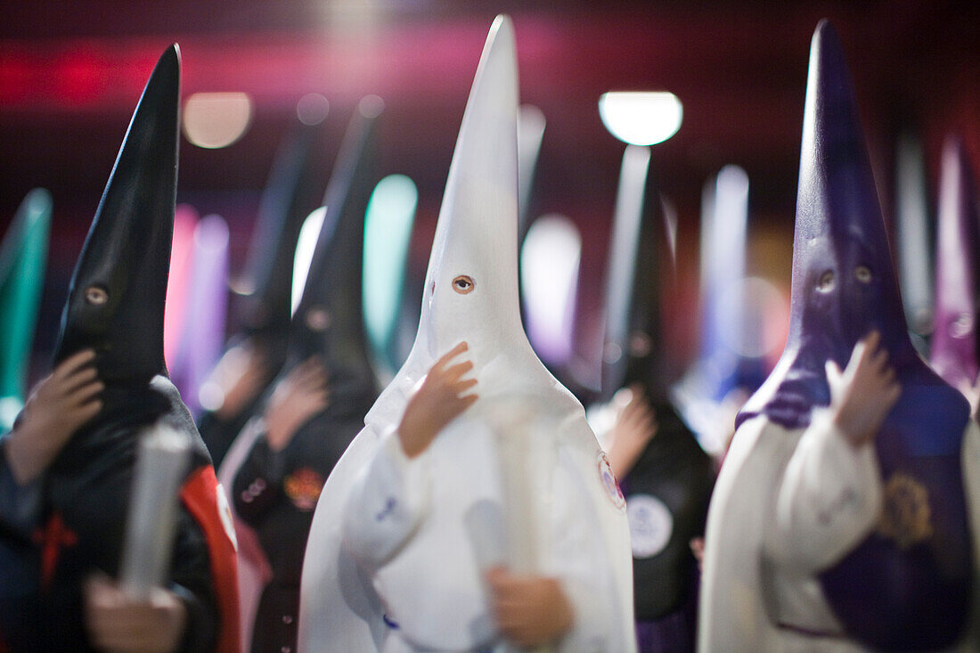 Colorful nazareno figures adorn a shop specializing in Semana Santa items in Seville, showcasing local traditions.