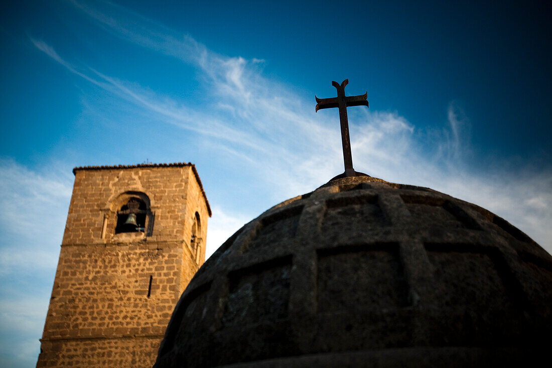 A globe-shaped fountain stands in San Nicolás square, complemented by the historic church in the backdrop under a blue sky.