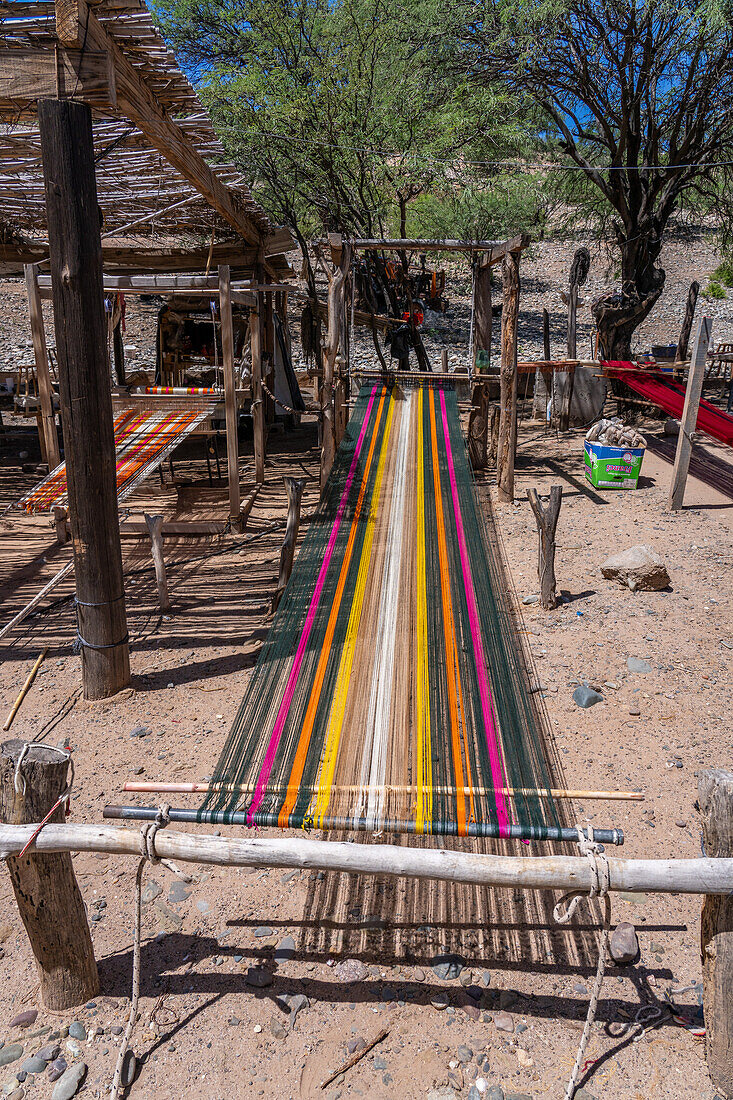 Buntes Garn auf einem hölzernen Fußwebstuhl in einer Heimweberei in Seclantas, Argentinien im Calchaqui-Tal