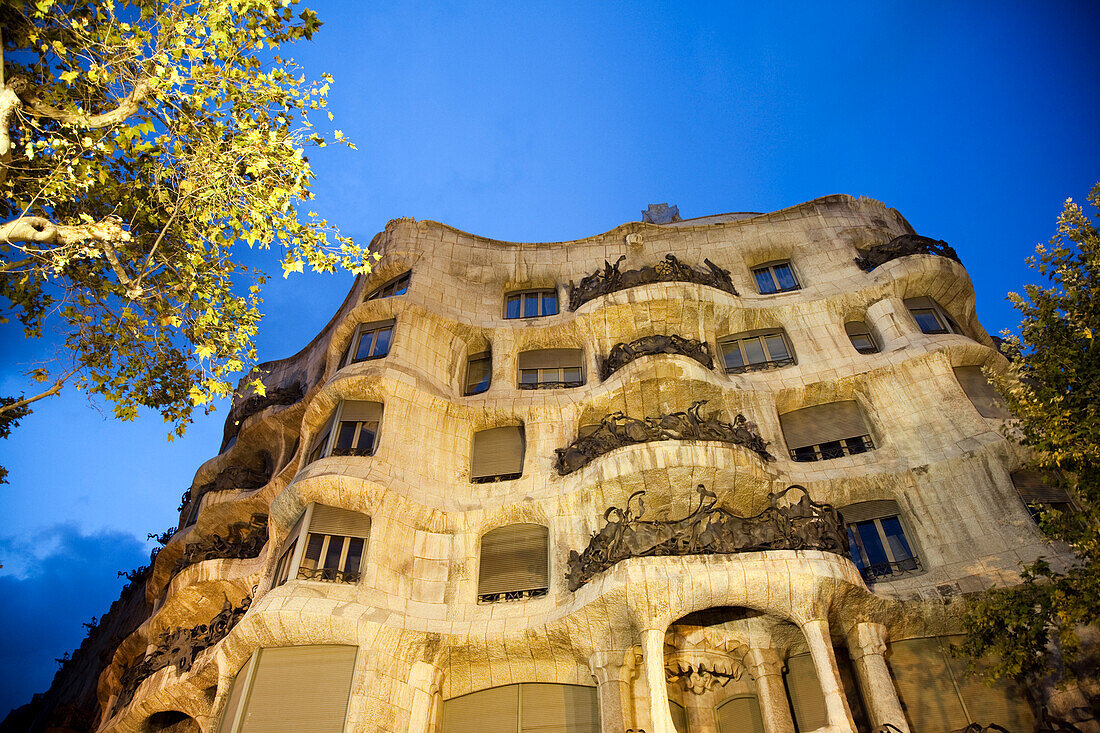 Explore the stunning architecture of Gaudi's La Casa Mila, beautifully lit up on a night in Barcelona, highlighting its unique design on the Paseo de Gracia.