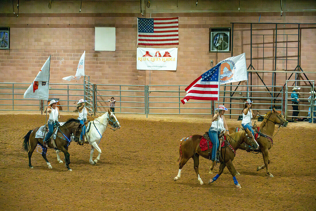 Cowgirls in einem berittenen Drillteam führen mit Fahnen den Grand Entry des Moab Junior Rodeo in Moab, Utah, vor