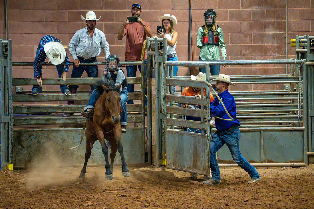 A young cowgirl rides a bucking horse at the Moab Junior Rodeo in Moab, Utah.