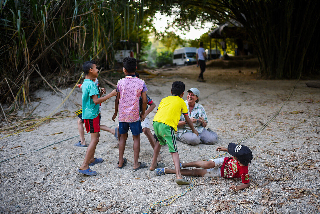 Eine Gruppe verspielter einheimischer Kinder hat Spaß mit einer Ausländerin, Santa Marta, Kolumbien