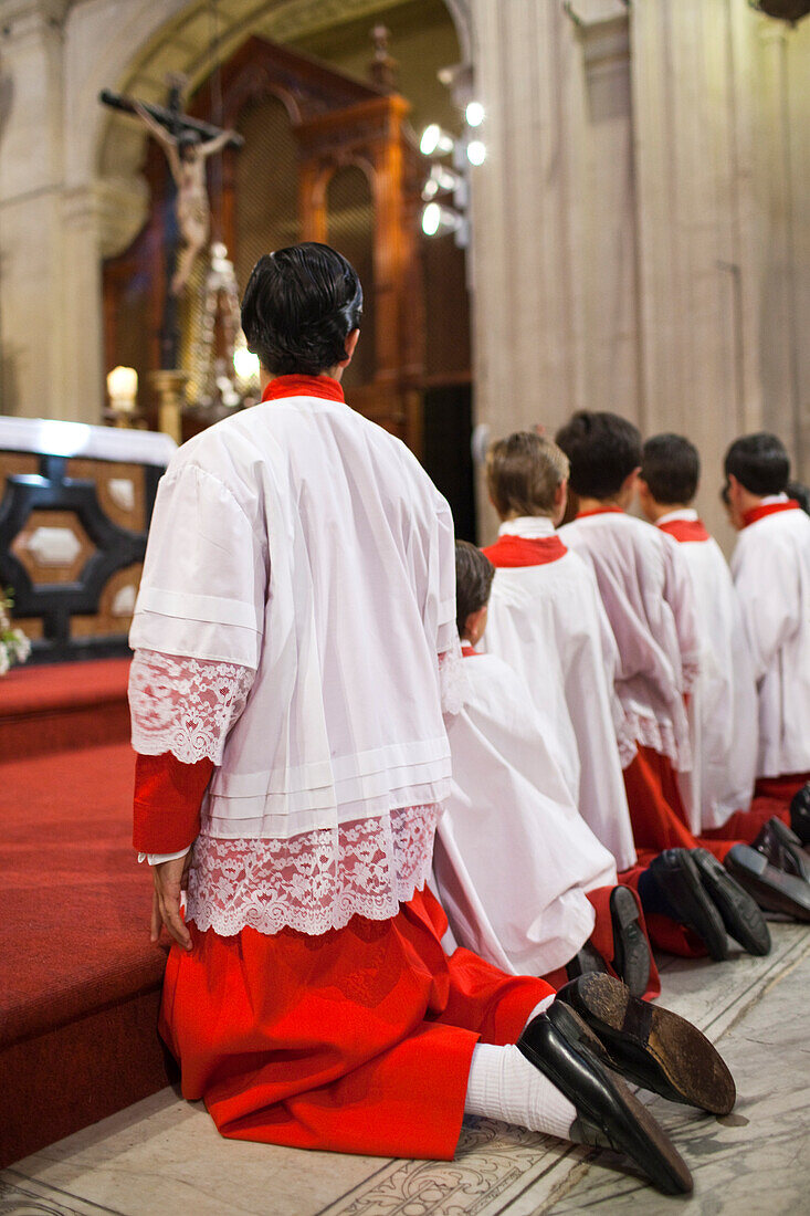 Altar boys kneel in prayer at Sagrario church after the Corpus Christi procession in Seville, reflecting their devotion in 2009.