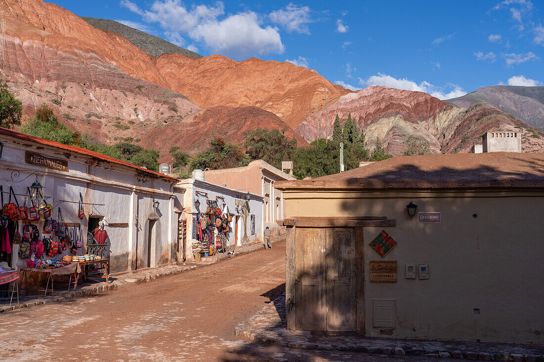 Touristenläden in der Calle Florida in Purmamarca, Argentinien, mit dem Hügel der Sieben Farben im Hintergrund