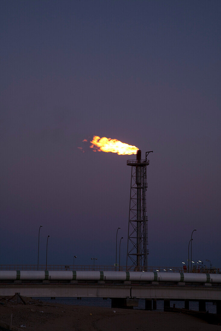 Gas flare burns brightly at the regasification plant along the coast, illuminating the evening sky in Huelva, southwestern Spain.