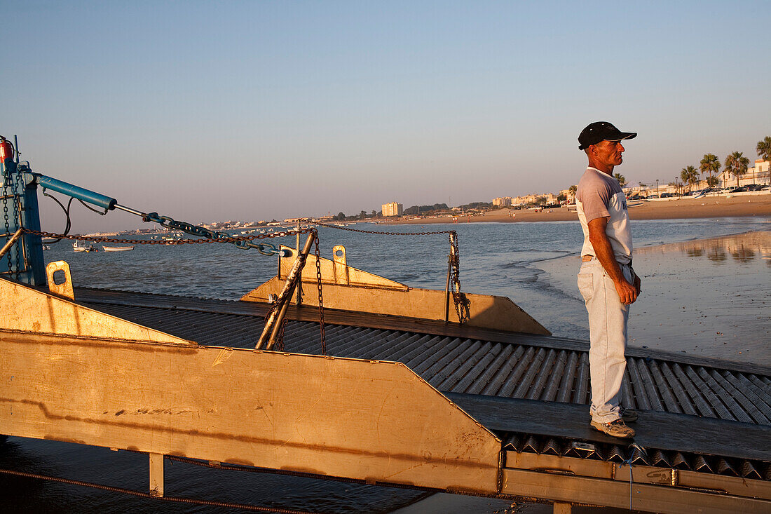 Seville, Spain, Aug 7 2008, A sailor prepares to navigate the barge across the Guadalquivir river at Bajo de Guia beach during sunset in Sanlucar de Barrameda.