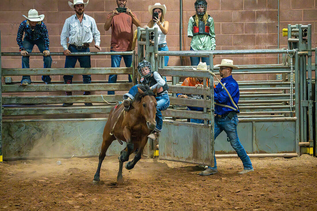 A young cowgirl loses her balance on a bucking horse at the Moab Junior Rodeo in Moab, Utah.