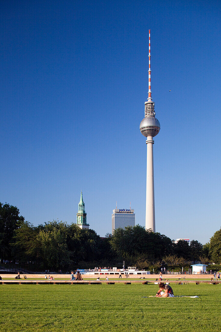 Enjoy a sunny day at Schlossplatz Park, featuring Berlin\'s iconic TV Tower and St. Mary?s Church amidst green lawns.