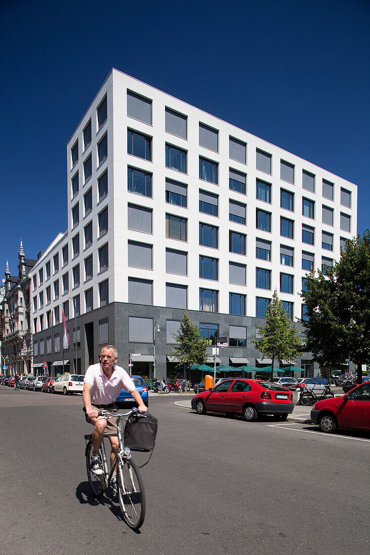 Berlin, Germany, July 27 2009, A cyclist rides past a striking contemporary building on Friedrichstrasse, showcasing Berlin\'s urban landscape and architecture.