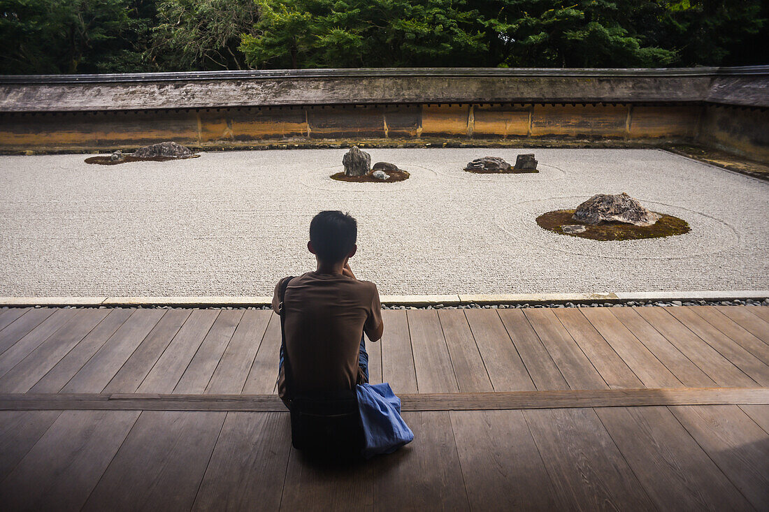 Ein Mann meditiert im japanischen Zen-Garten, dem Ryoan-Ji-Tempel in Kyoto