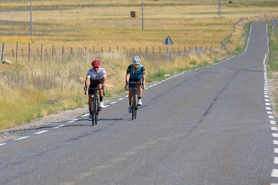 Two riders cycling in the road of La Lancha, a mountain pass in the province of Ávila.