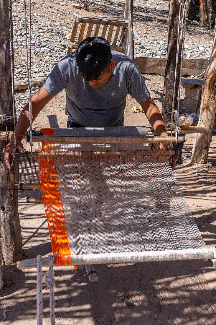 A young man weaving on a wooden foot loom in Seclantas, Argentina in the Calchaqui Valley.