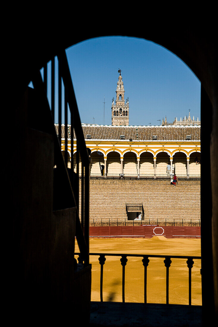 The Maestranza bullring in Seville is framed by an archway, showcasing its historic architecture and vibrant atmosphere under sunny skies.