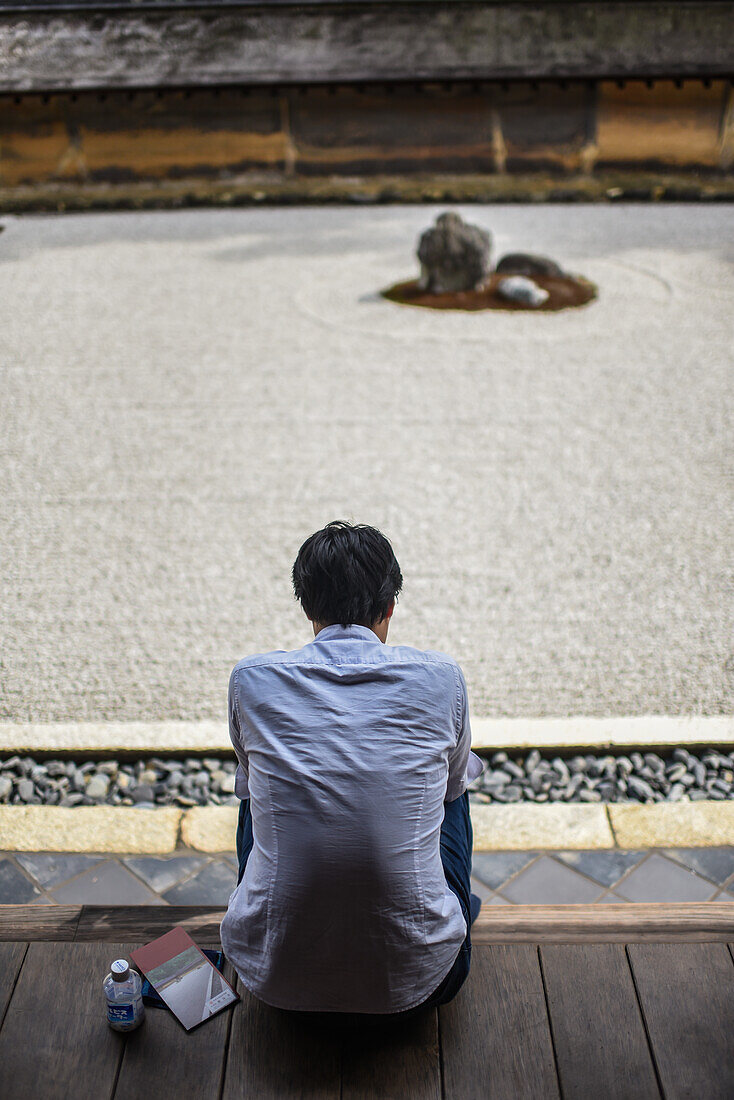 Ein Mann meditiert im japanischen Zen-Garten, Ryoan-Ji-Tempel in Kyoto