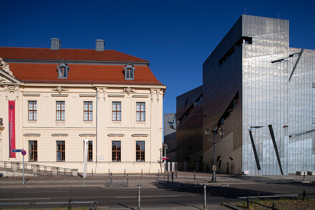 Das Jüdische Museum in Berlin zeichnet sich durch seine vielfältige Architektur aus, bei der sich historische und moderne Bauwerke vor einem klaren blauen Himmel abheben